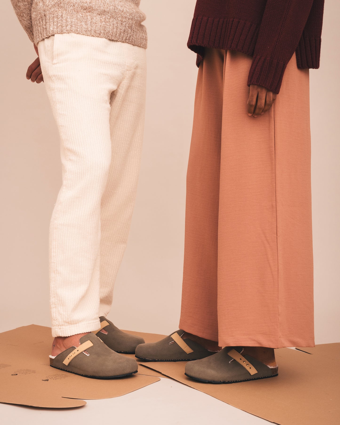 Two people wearing green clogs on a plain background
