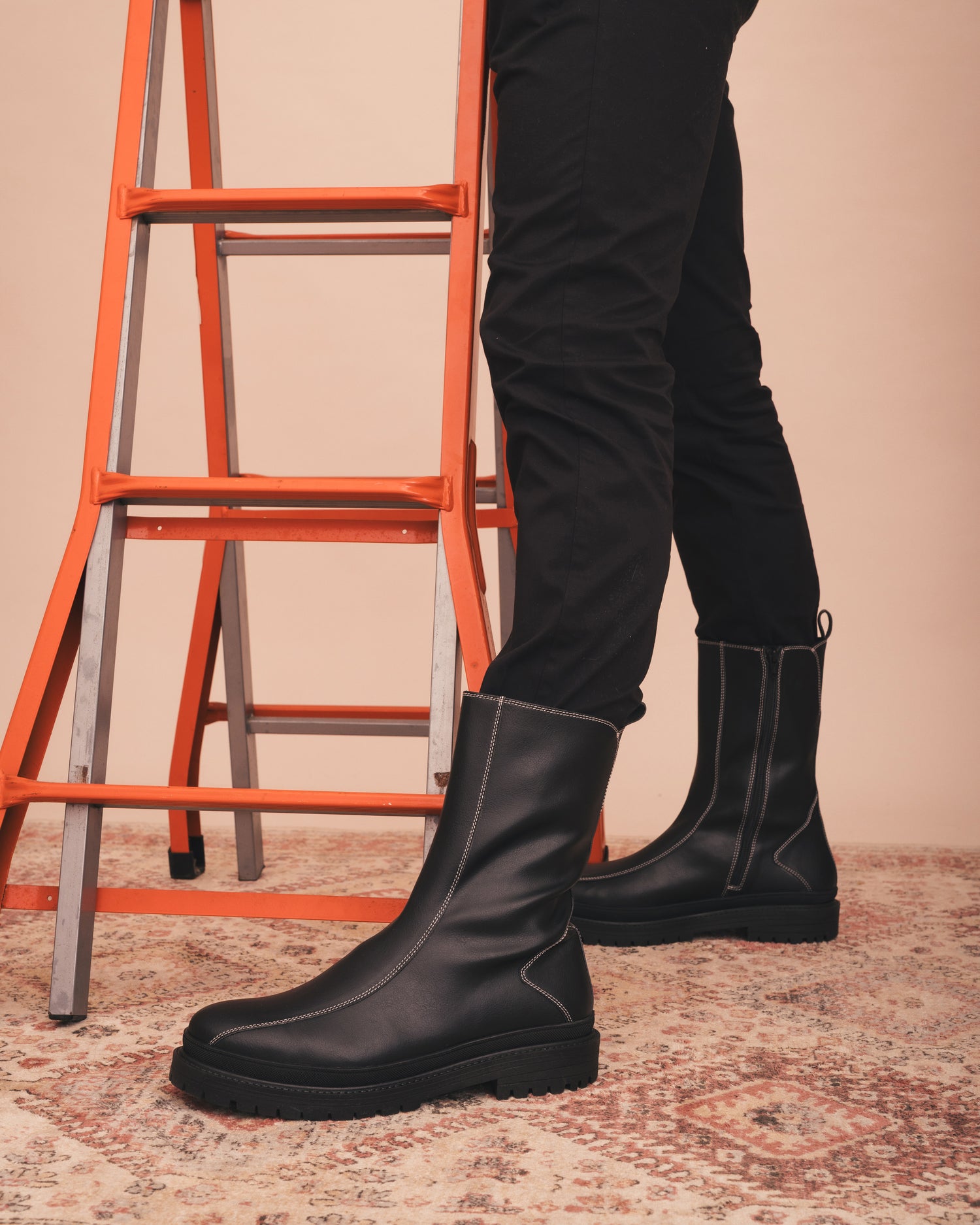Person wearing black boots with a red ladder in the background