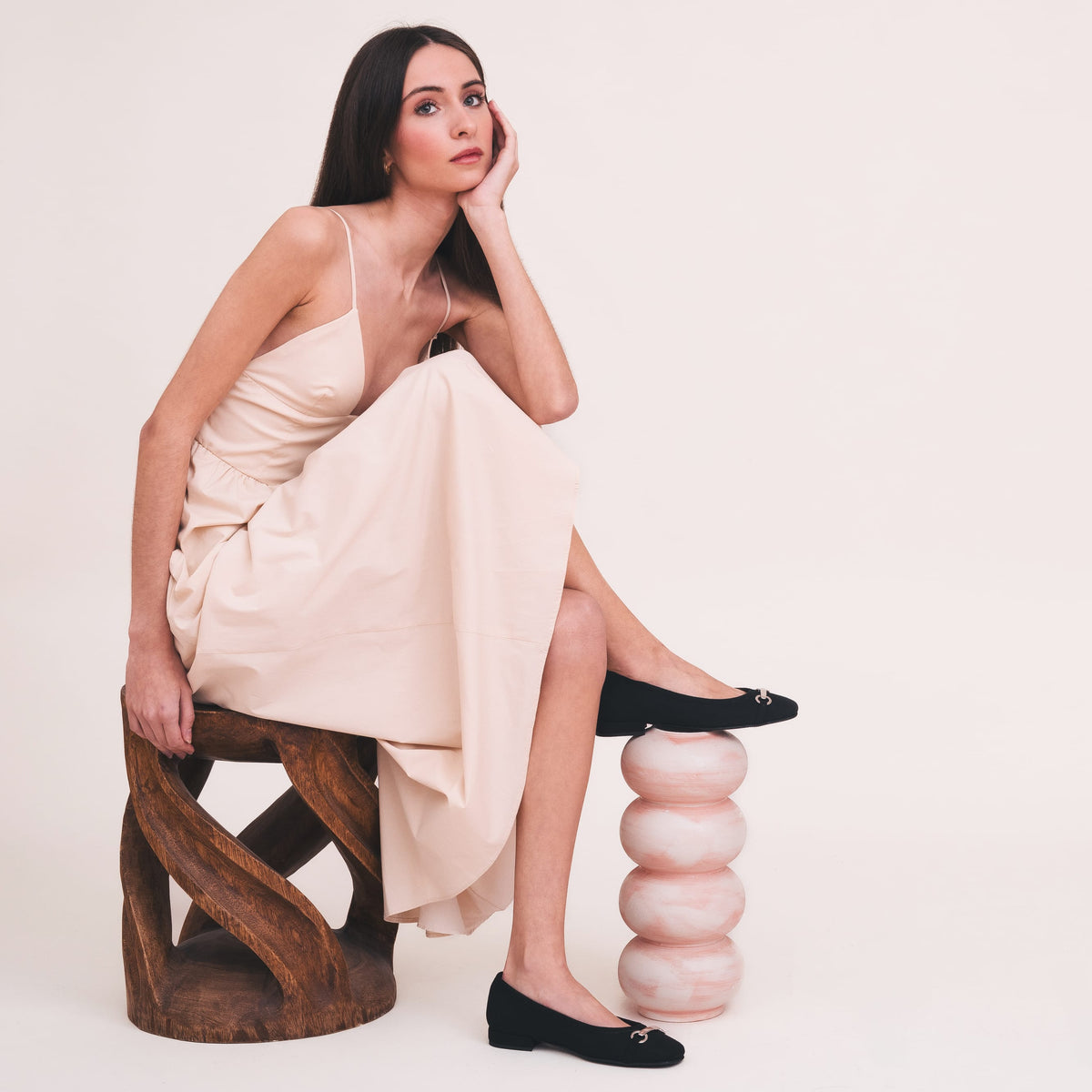 Woman sitting on a unique chair with a plain background