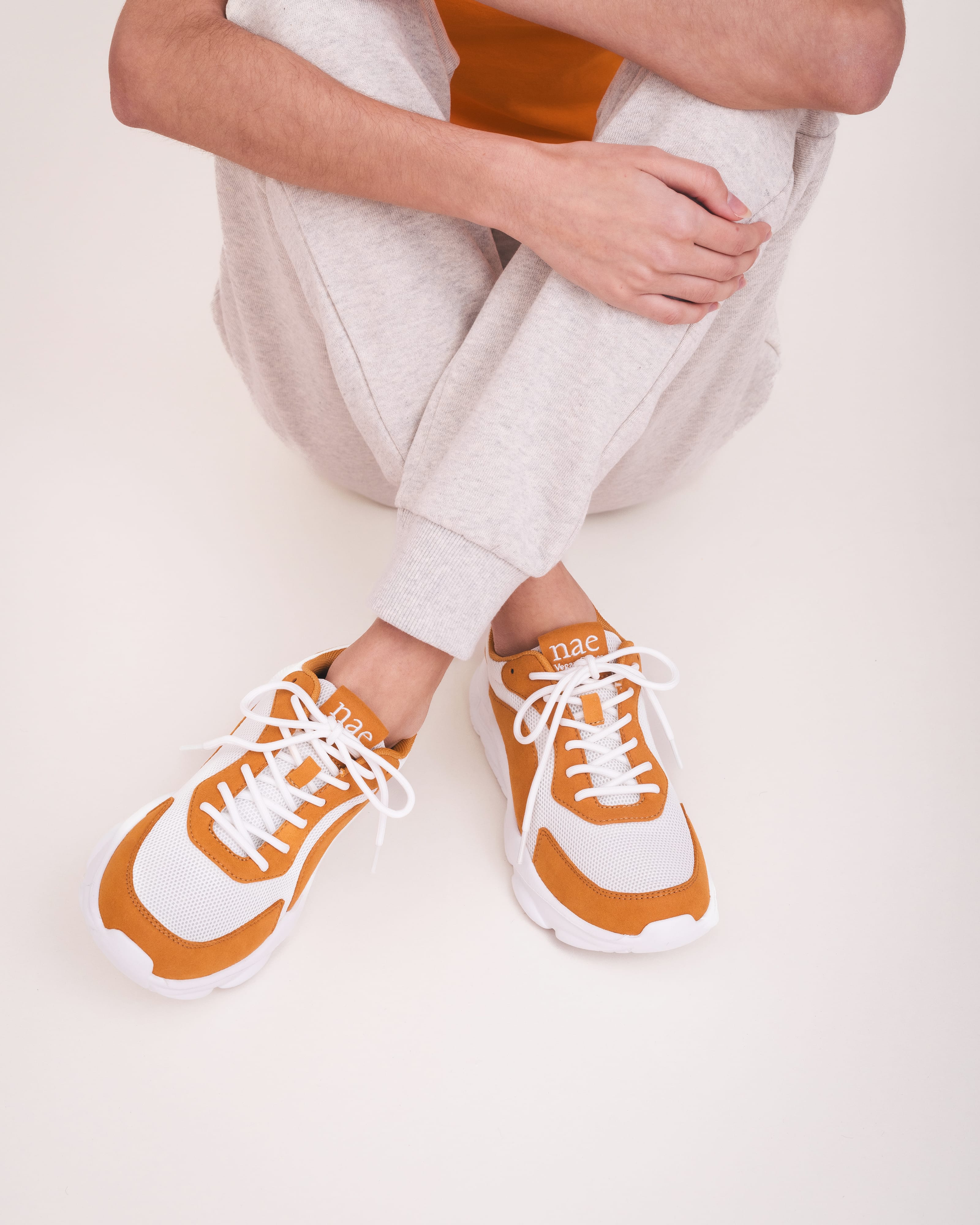 Person wearing orange and white sneakers on a light background