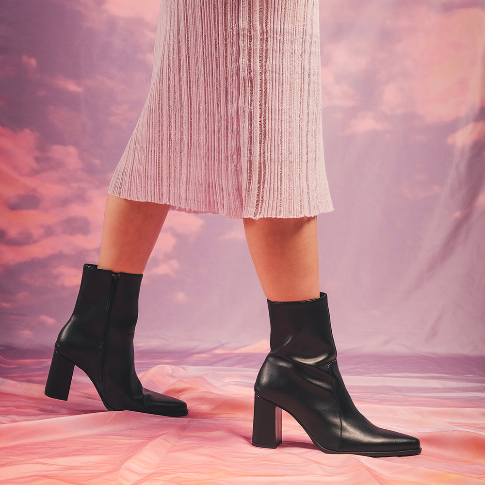 Women black ankle boots heels with zip wearing sustainable dress on cloud background | NAE Footwear