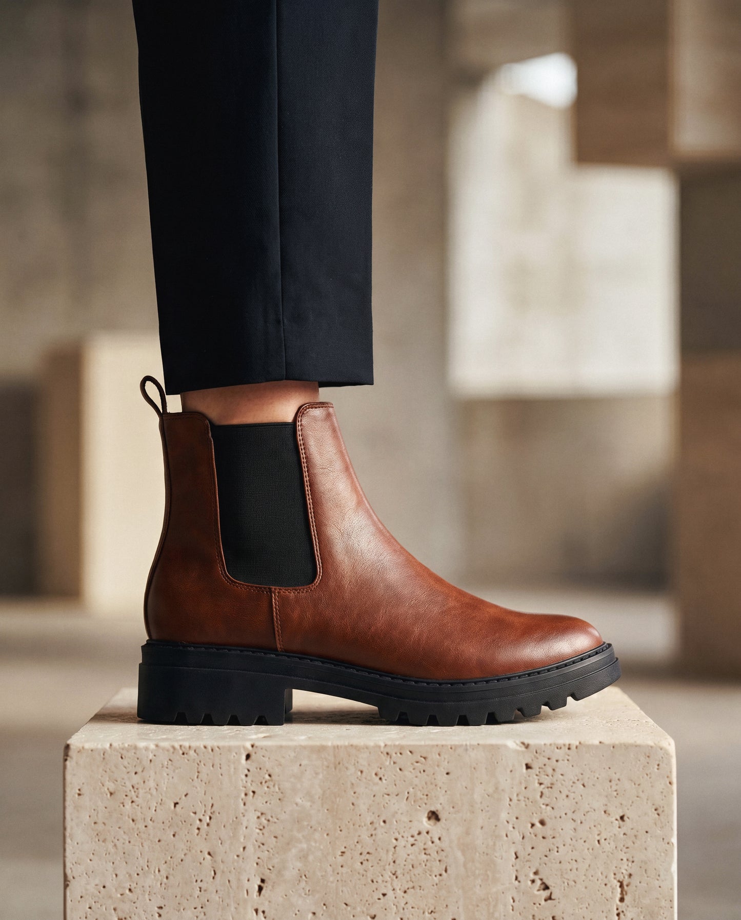 Brown vegan leather boot with black sole on a stone block, blurred background | NAE Vegan Shoes