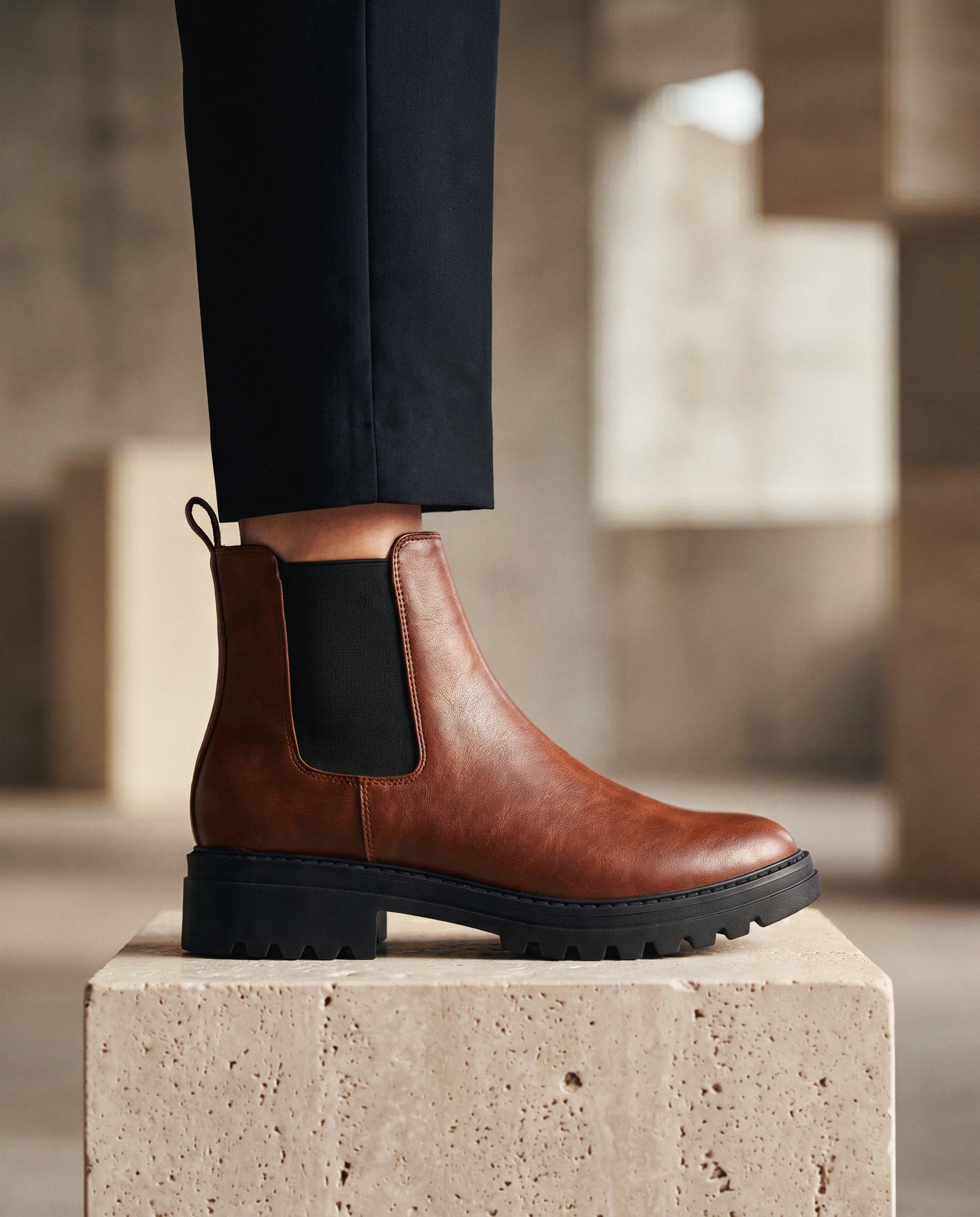 Brown vegan leather boot with black sole on a stone block, blurred background | NAE Vegan Shoes