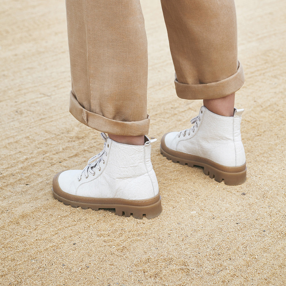 Women wearing white vegan ankle boots with beige pants | NAE Shop